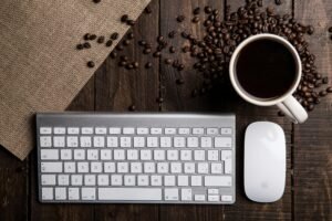Top view of a coffee cup with keyboard and mouse on a rustic wooden desk.