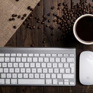 Top view of a coffee cup with keyboard and mouse on a rustic wooden desk.